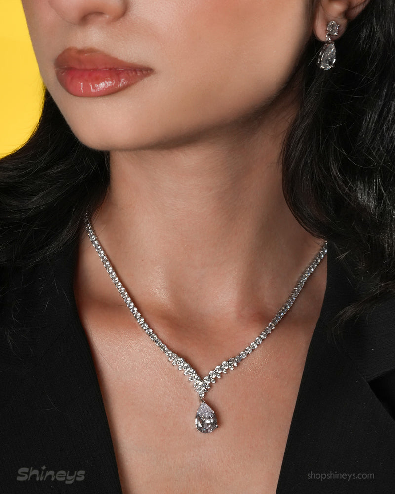A jewelry set with a graceful V-shaped line of white zircons and a shimmering teardrop centerpiece