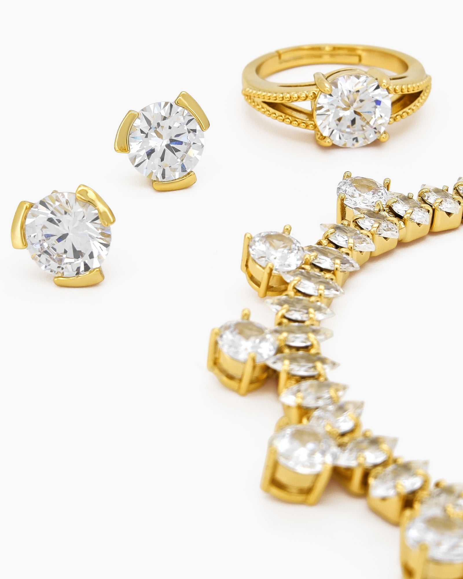 A jewelry set with a collar necklace, bracelet, earrings, and ring, all in gleaming gold tones