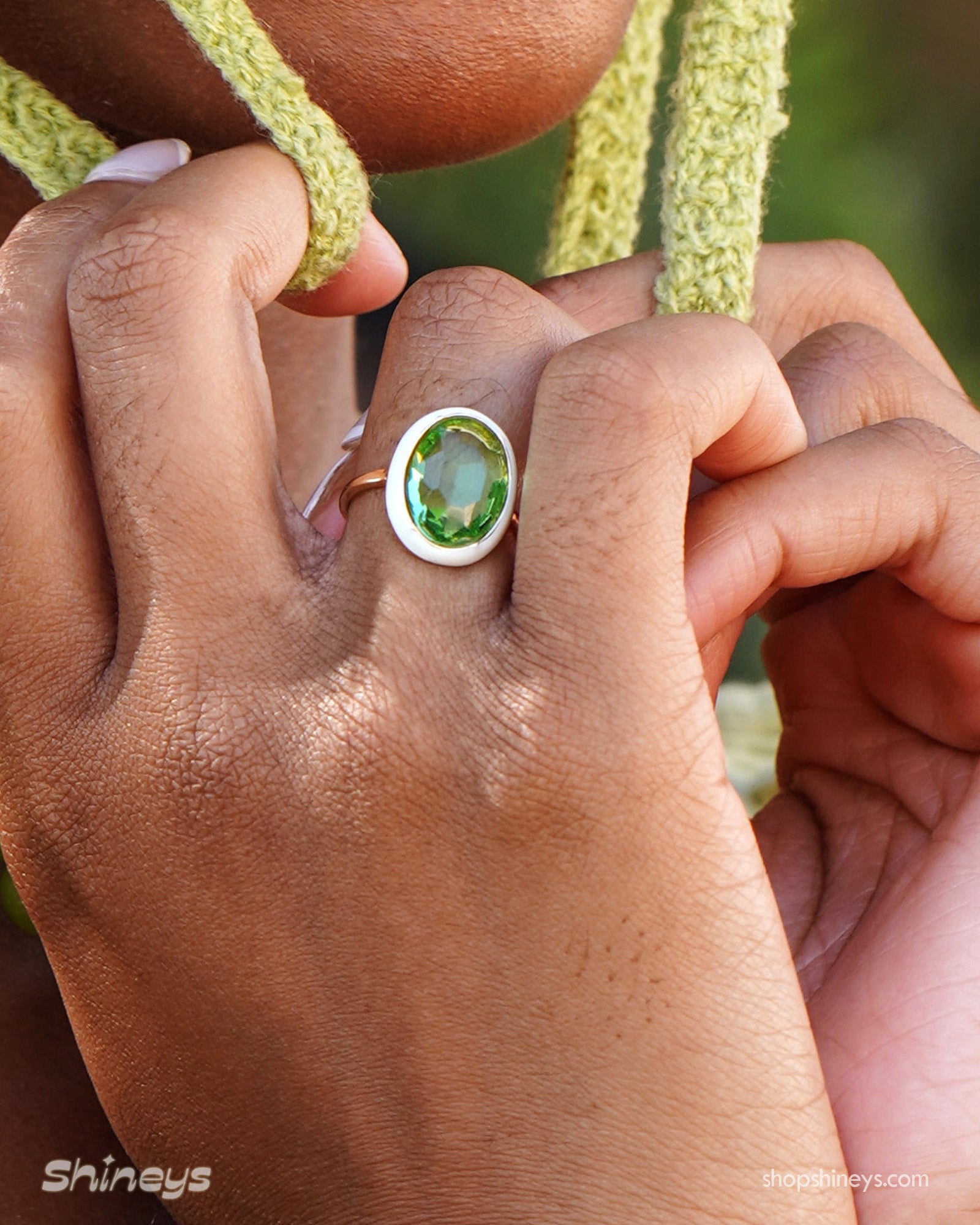 A green-white cocktail ring with a large, faceted oval stone framed by a glossy enamel halo on a gold band