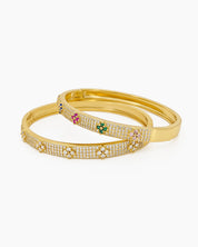 A gold bangle with a sleek silhouette, adorned with pavé-set crystals and playful multicolored floral motifs