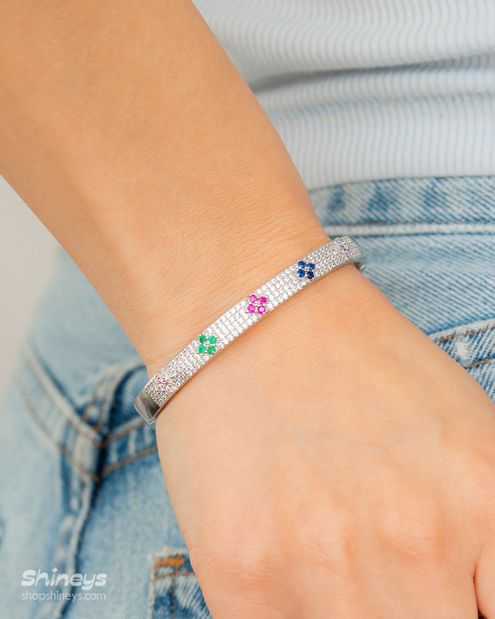 A silver bangle with a sleek silhouette, adorned with pavé-set crystals and playful multicolored floral motifs
