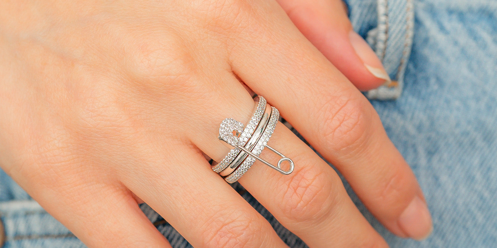A silver stacked band ring with a crystal-studded safety pin detail for a stylish, daring twist