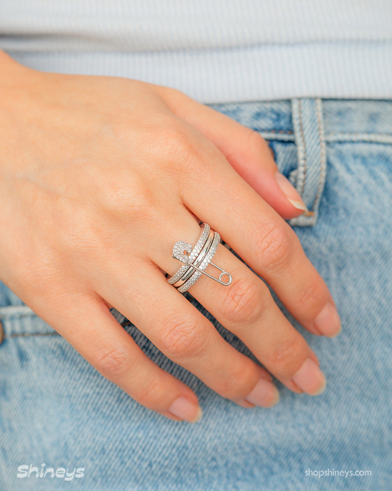 A silver stacked band ring with a crystal-studded safety pin detail for a stylish, daring twist