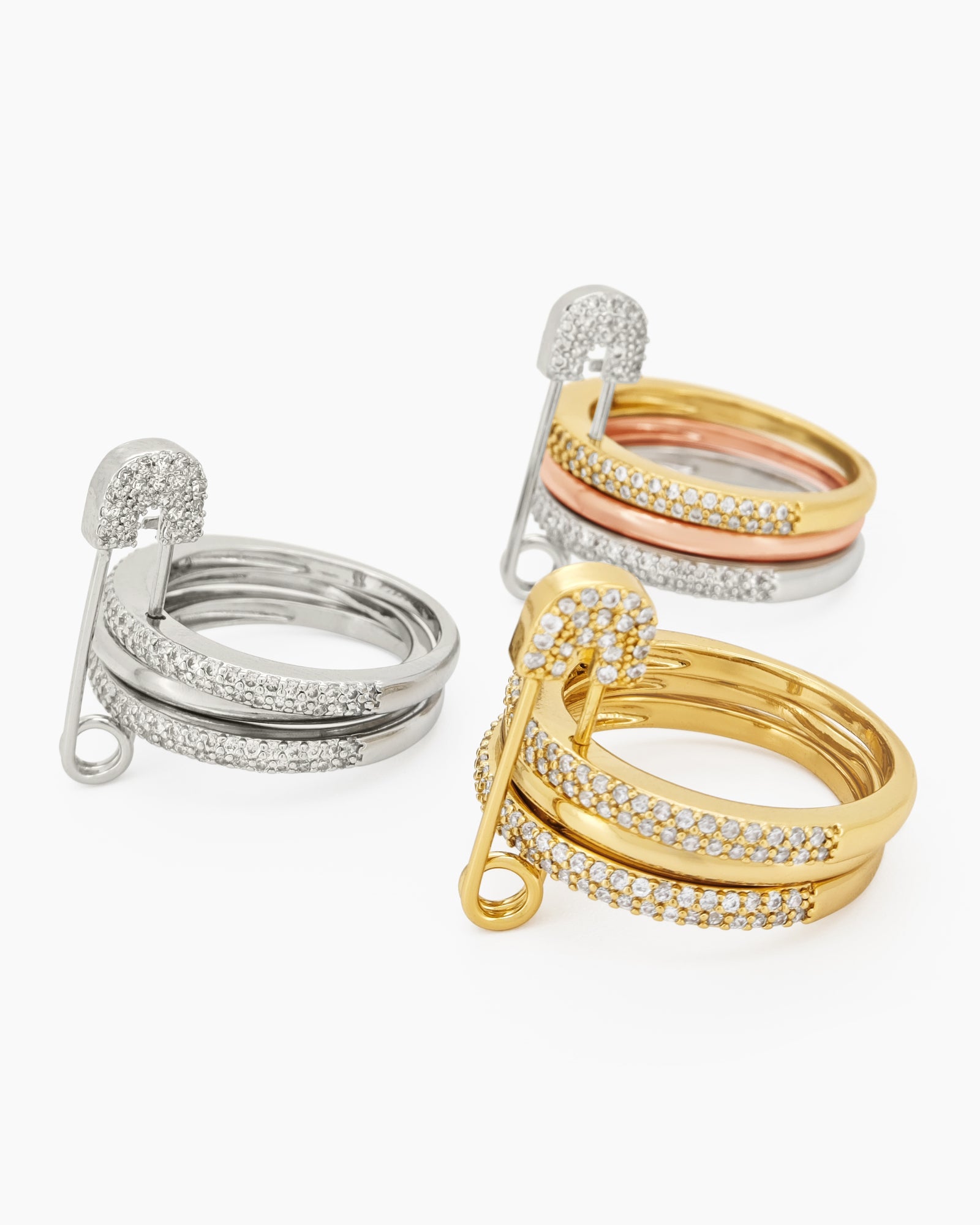 A gold stacked band ring with a crystal-studded safety pin detail for a stylish, daring twist