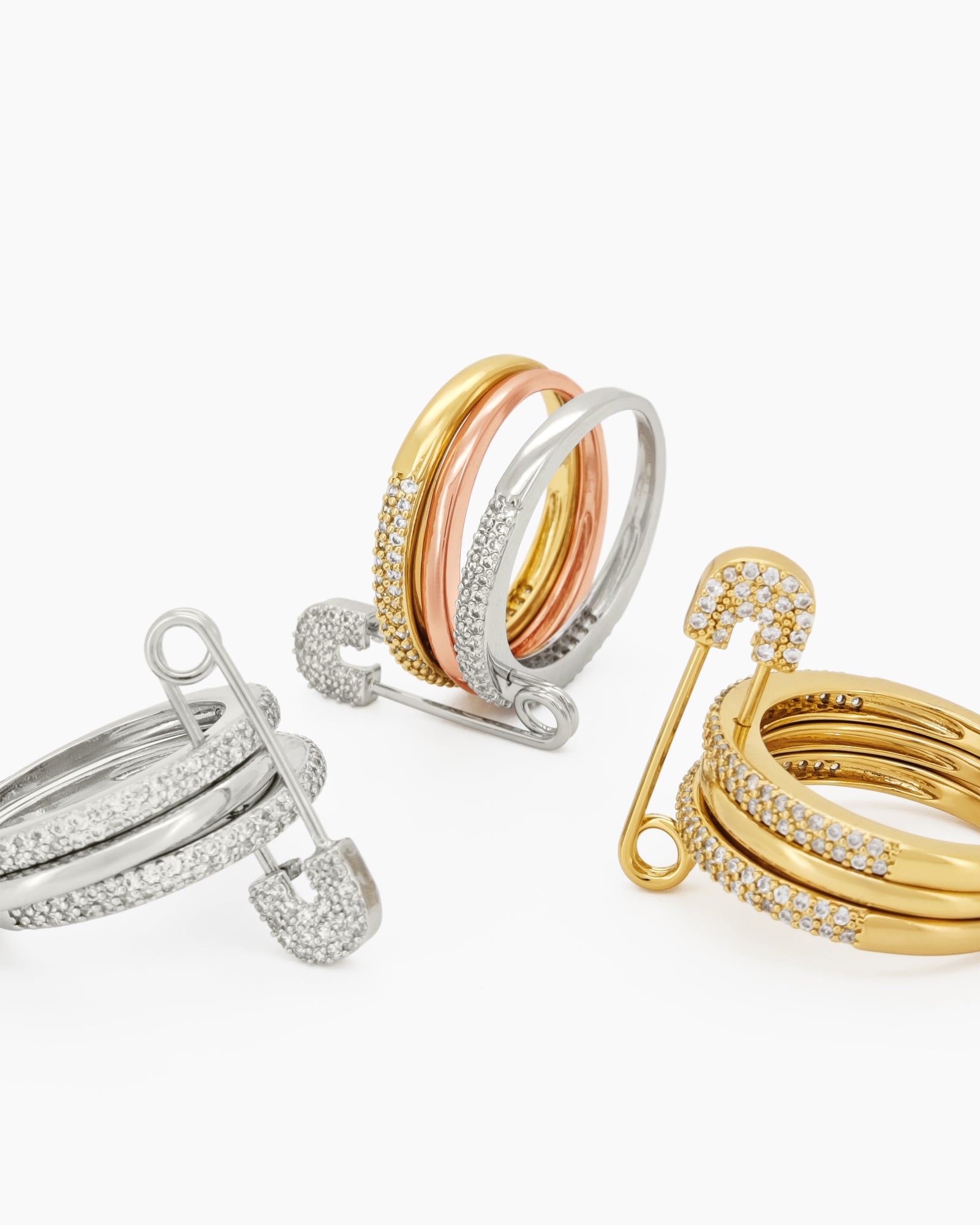 A gold stacked band ring with a crystal-studded safety pin detail for a stylish, daring twist