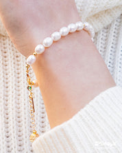 A bracelet of lustrous freshwater pearls and polished gold-toned beads with a trio of statement charms