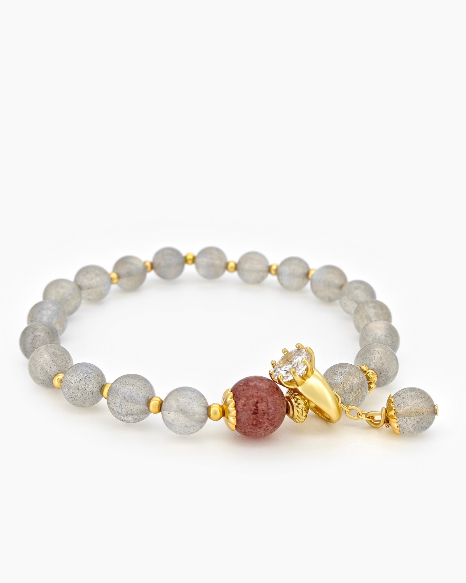 A bracelet of hand-strung natural moonstone beads with a single strawberry quartz bead and golden accents