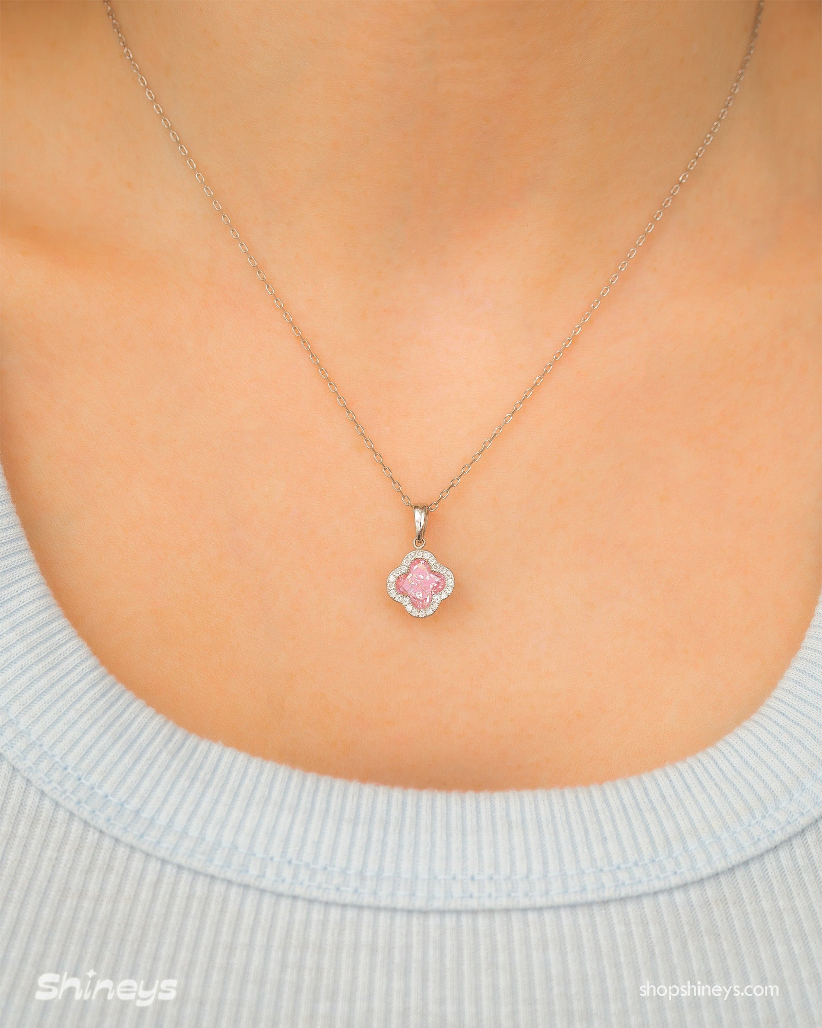 A pink necklace with a clover pendant outlined in pavé zircons and a faceted four-petal center stone