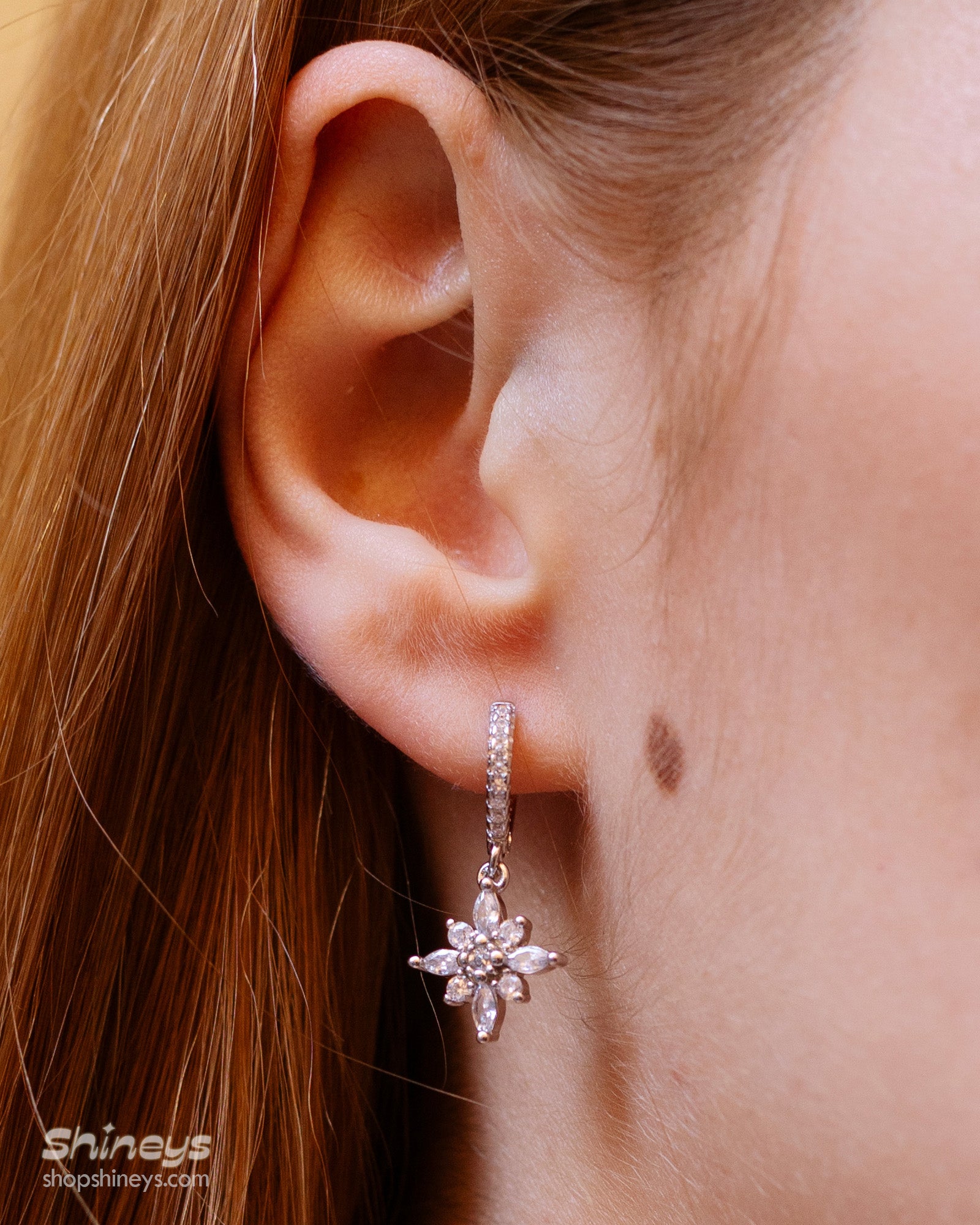 Silver huggie hoop earrings with a dainty flower-shaped charm crafted from marquise and round white zircons