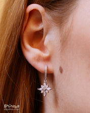 Silver huggie hoop earrings with a dainty flower-shaped charm crafted from marquise and round white zircons