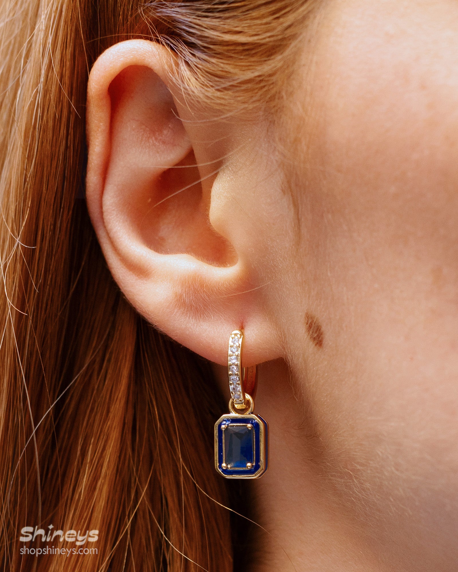 Sapphire-blue drop earrings with a radiant emerald-cut zircon framed by a glossy enamel border and a pavé hoop
