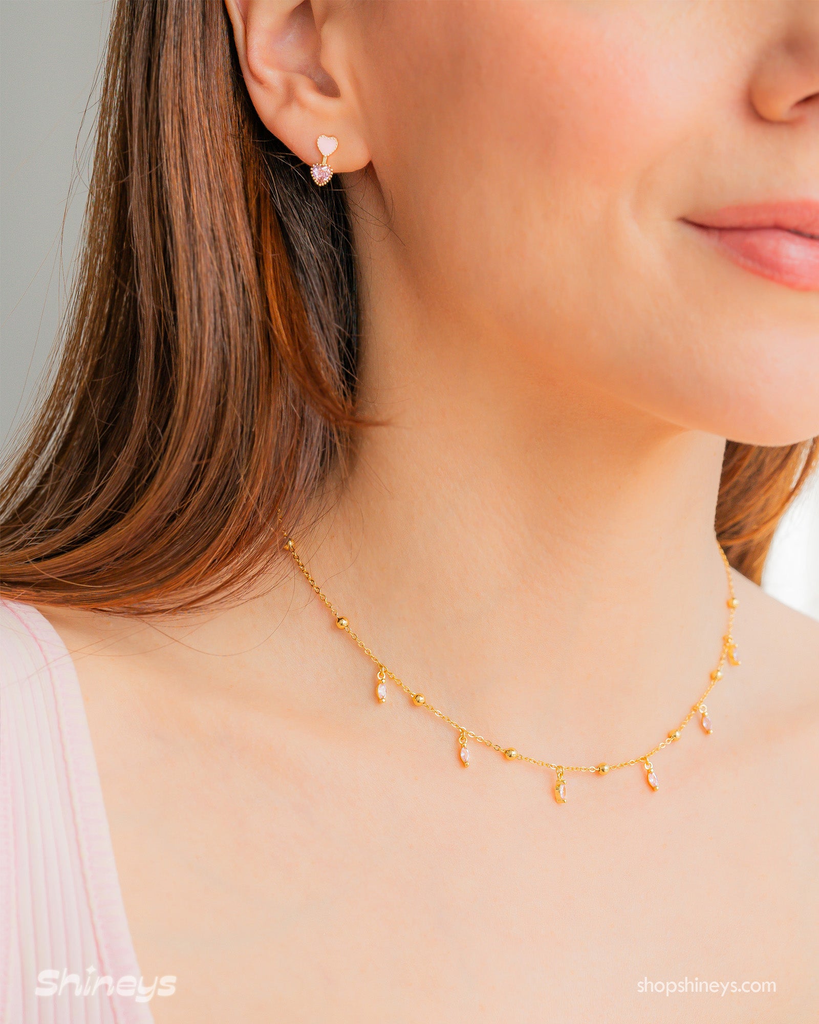 A choker with a delicate chain dotted with polished golden beads and dainty pink marquise-cut crystal drops