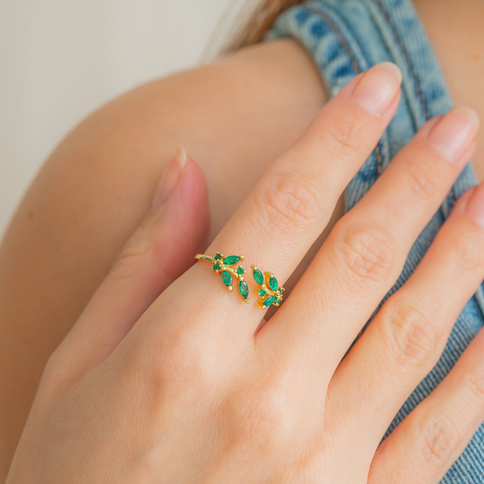 A green open ring with clusters of marquise-cut zircons that bloom from each side of the band