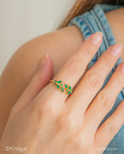 A green open ring with clusters of marquise-cut zircons that bloom from each side of the band