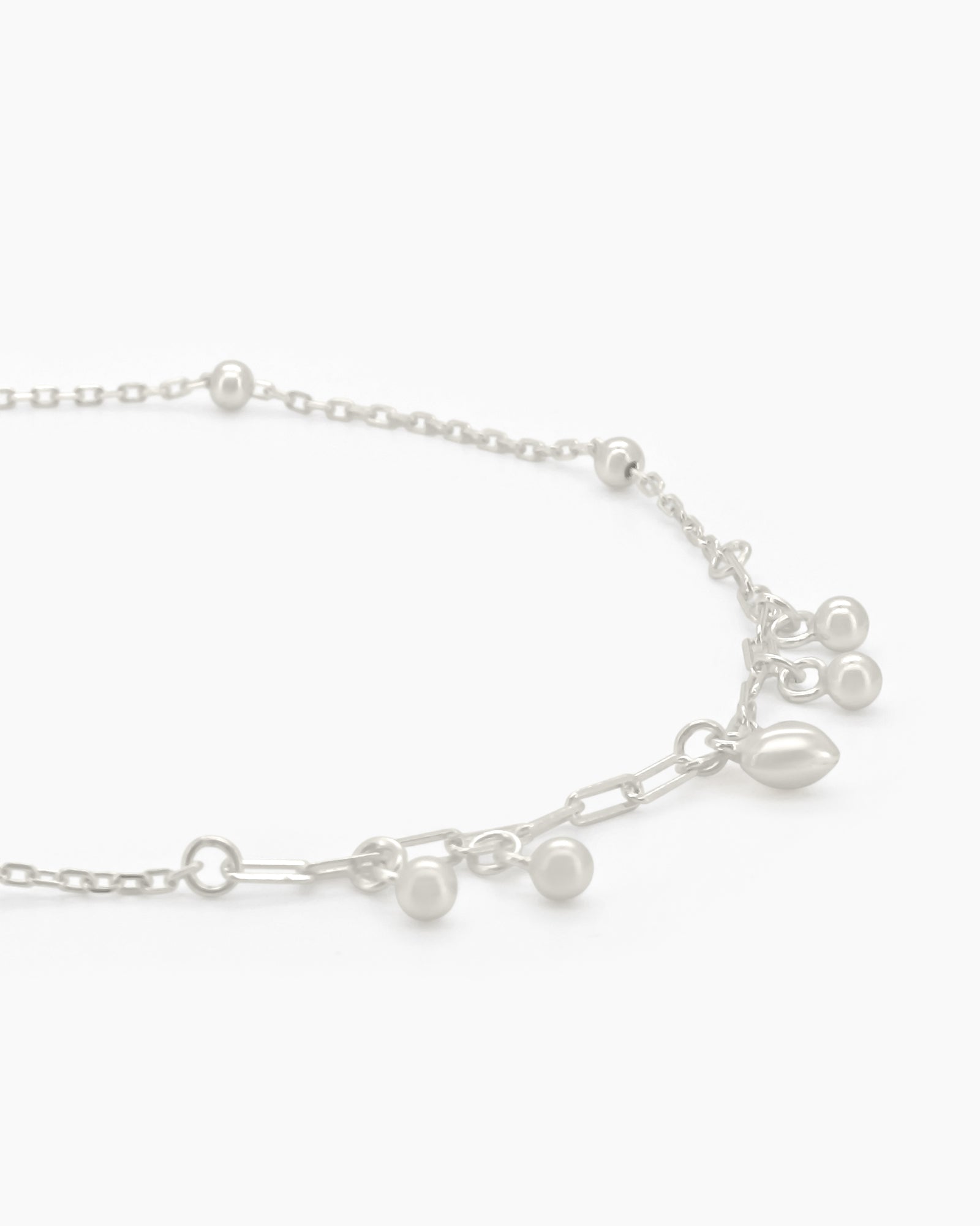 An adjustable 925 sterling silver anklet with a delicate chain, polished beads, and mini charms