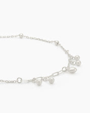 An adjustable 925 sterling silver anklet with a delicate chain, polished beads, and mini charms