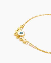 A sleek double-chain anklet with dainty gold discs and a central enamel evil eye for symbolic charm