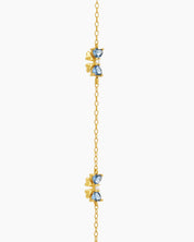 A dainty gold-toned bracelet with three tiny bows crafted from sparkling blue heart-cut zircons