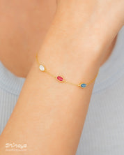An elegant bracelet with three bezel-set oval zircons, each in a unique hue, on a fine cable chain