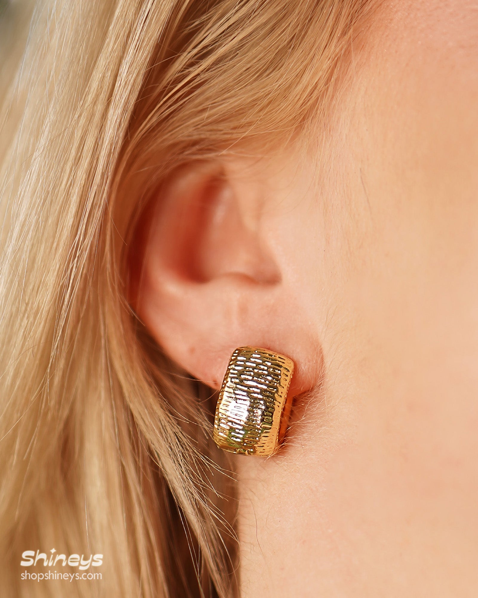 Chunky gold hoops with a sculpted, densely textured surface that creates depth and movement