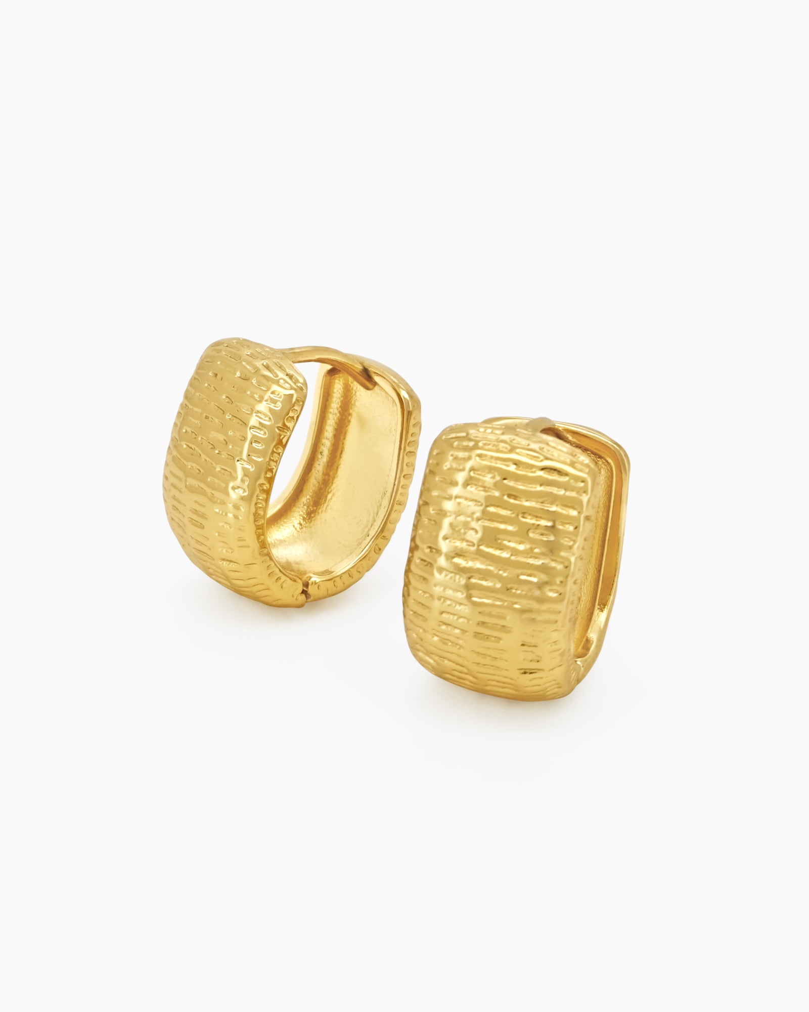 Chunky gold hoops with a sculpted, densely textured surface that creates depth and movement