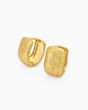 Chunky gold hoops with a sculpted, densely textured surface that creates depth and movement