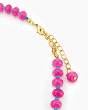 A beaded necklace with glossy fuchsia-toned quartz beads and petite turquoise-blue spacers