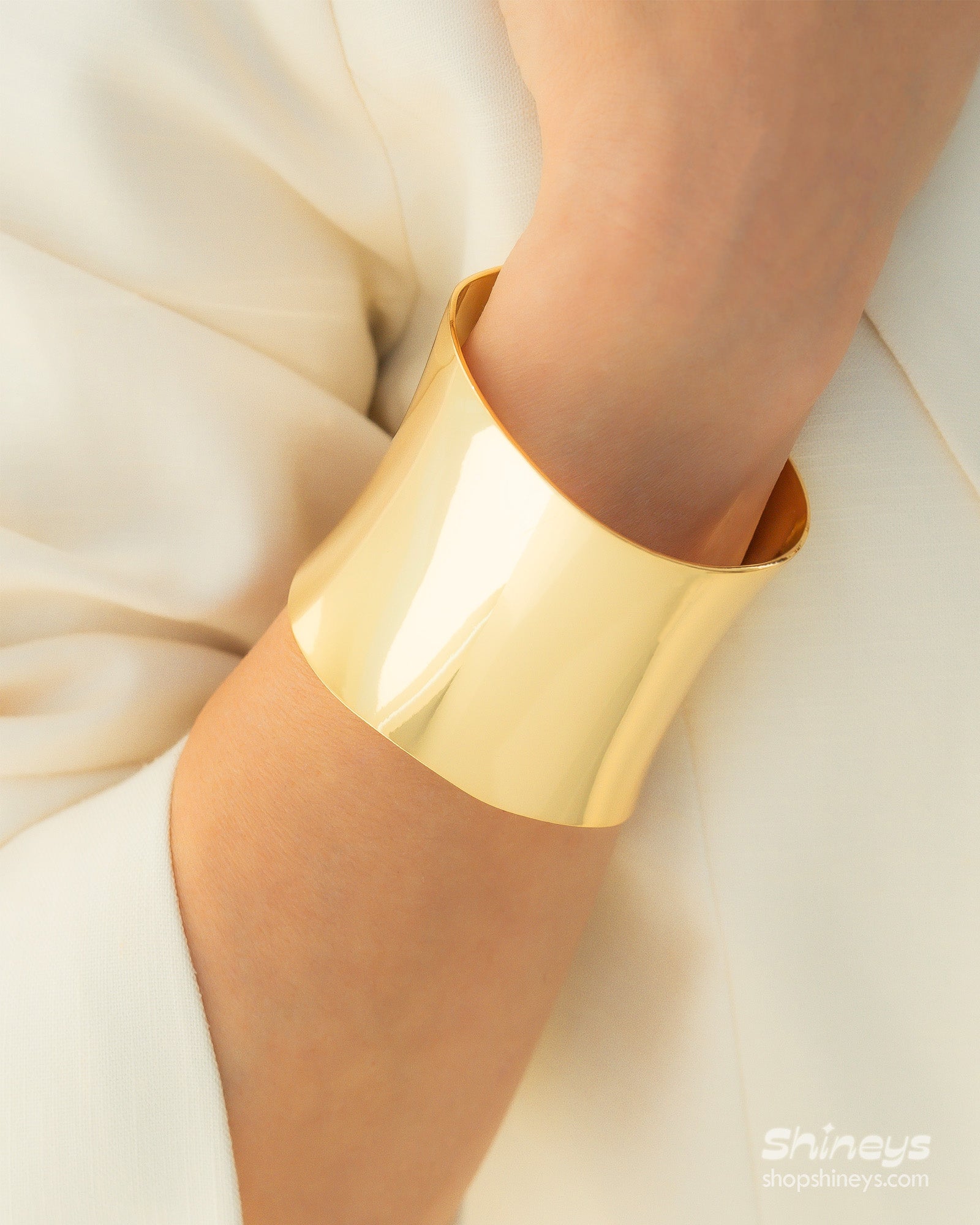 A gold open cuff with a wide, clean silhouette and a mirror-like finish for a minimalist, high-impact look
