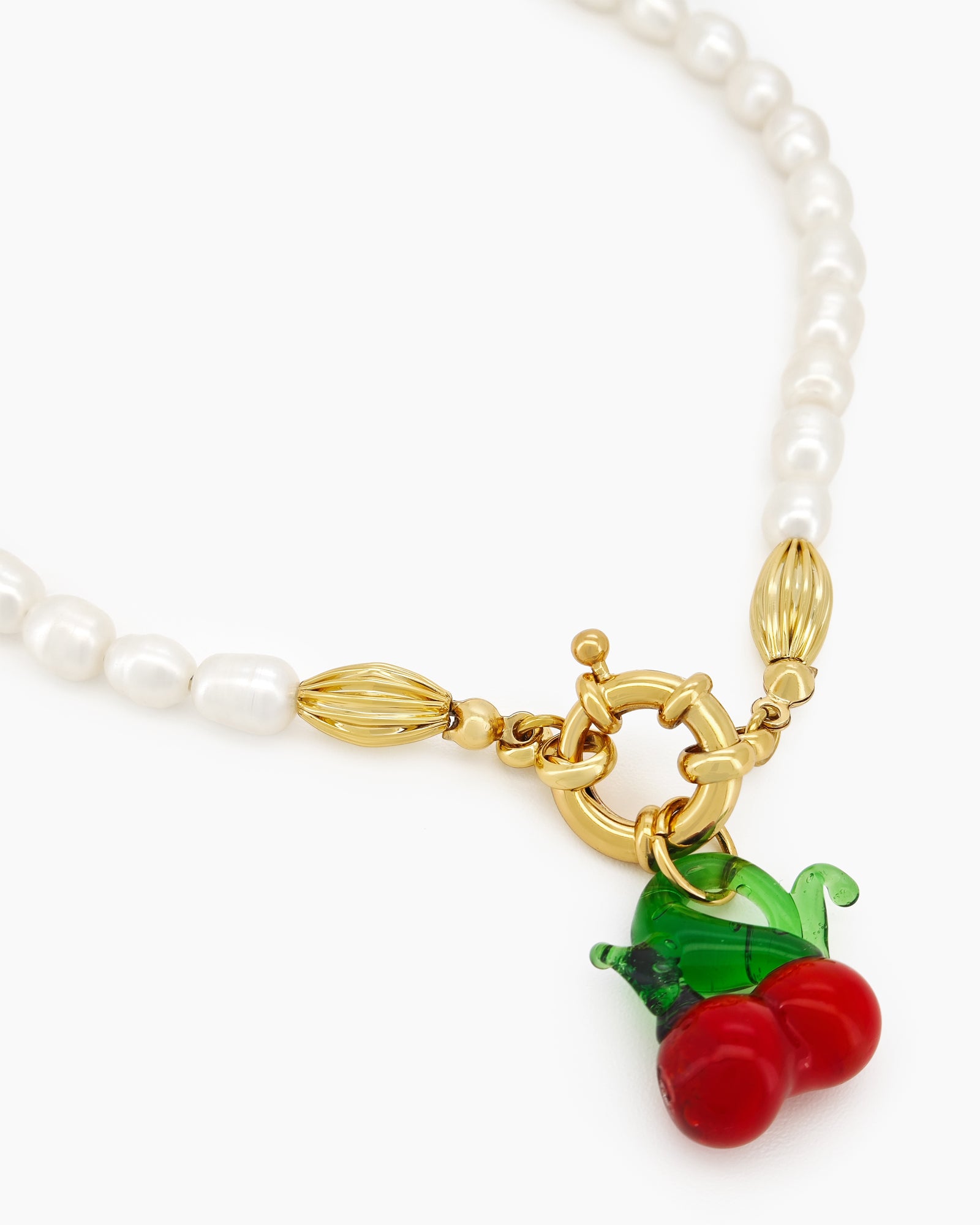 A necklace of timeless freshwater pearls with a glossy cherry pendant for a playful pop of color