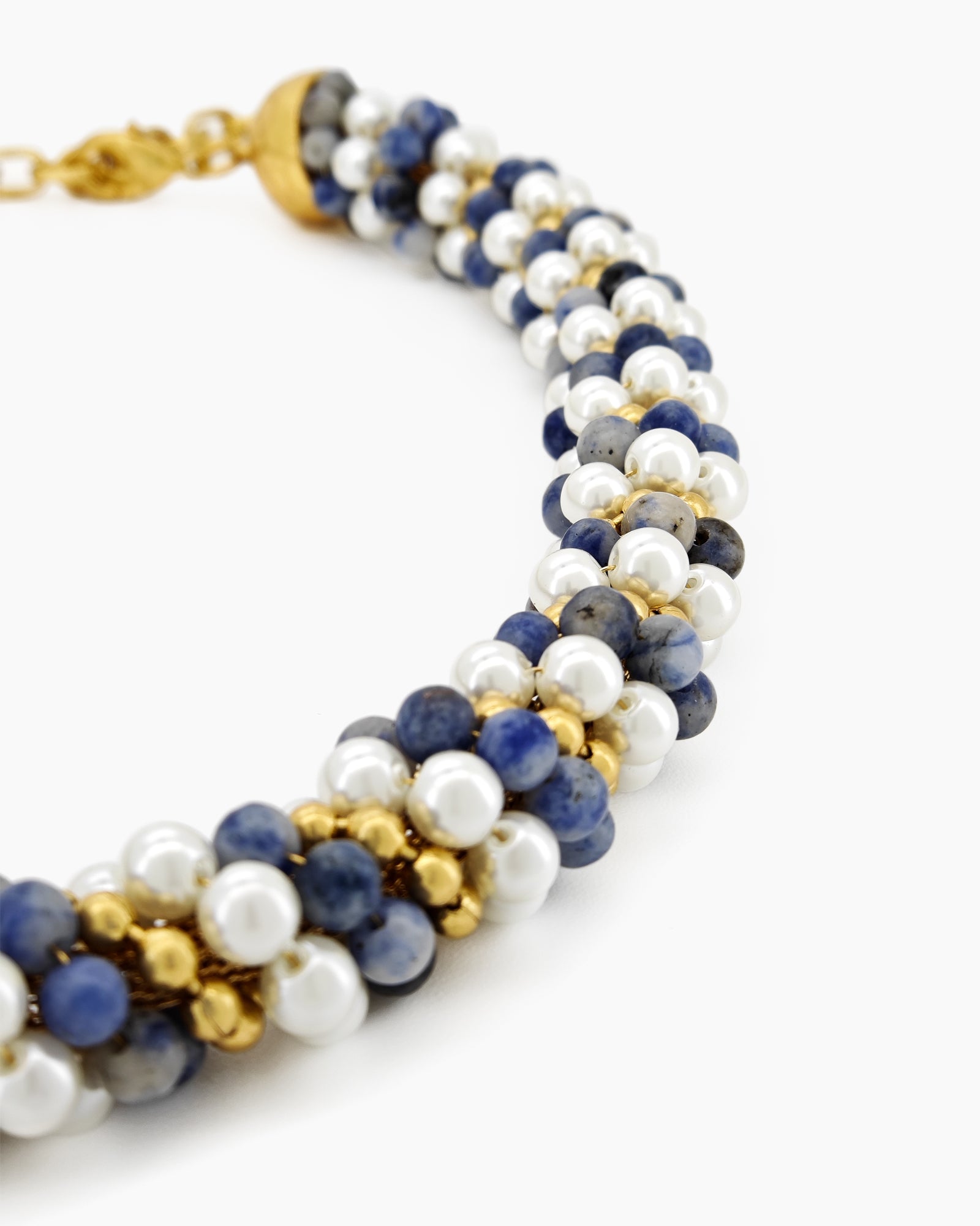 A swirling necklace of creamy pearls, twilight-hued beads, and golden accents twisted in a harmonious spiral