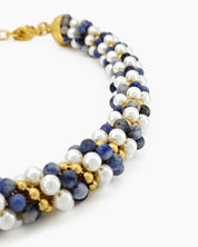 A swirling necklace of creamy pearls, twilight-hued beads, and golden accents twisted in a harmonious spiral