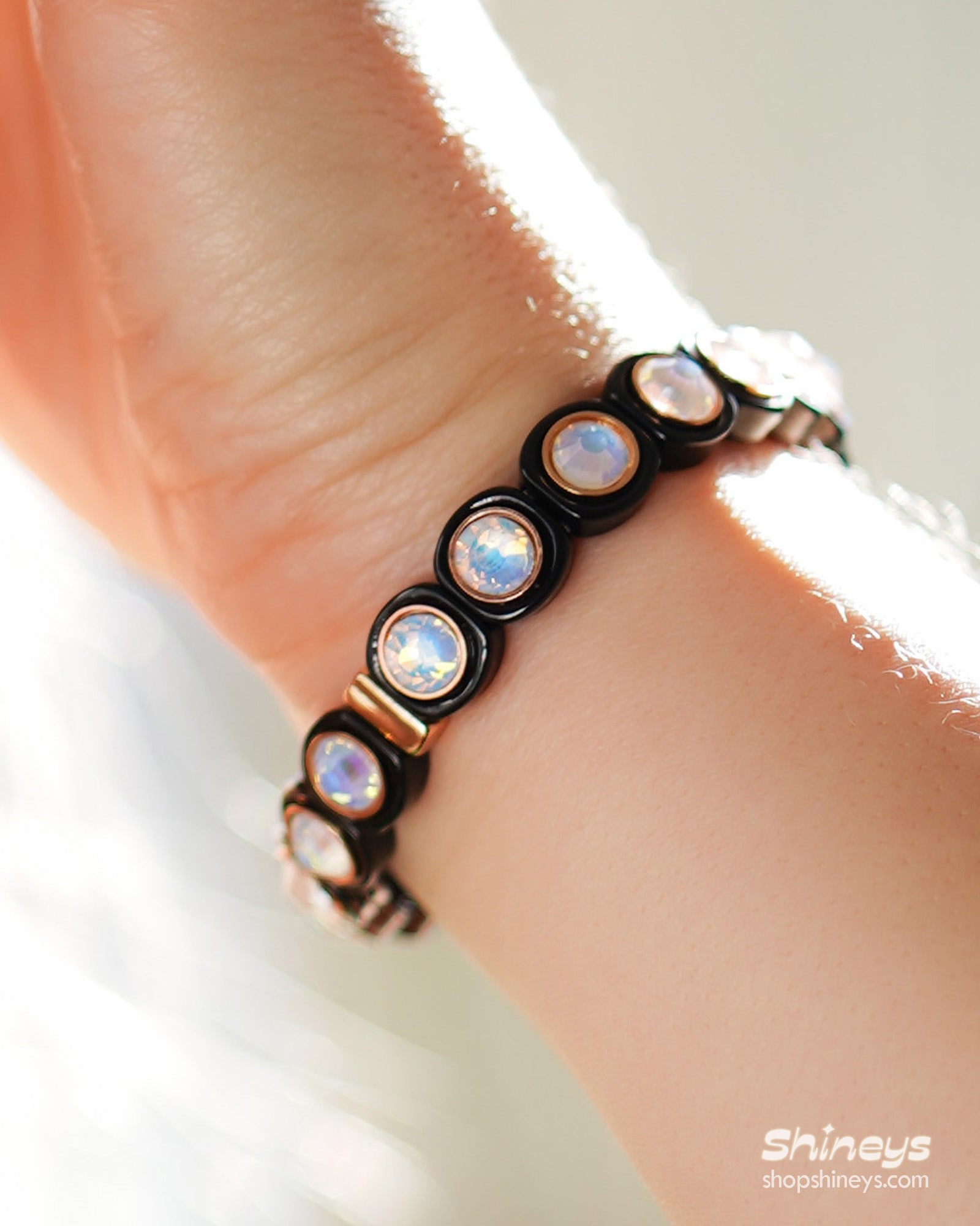 A black-white stretch bracelet with glossy links set with iridescent crystal stones for a playful flair