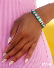 A green-pink stretch bracelet with glossy links set with iridescent crystal stones for a playful flair