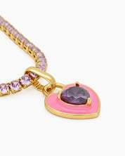 A light-pink tennis necklace with a full strand of zircon stones and an enamel heart charm with a center stone