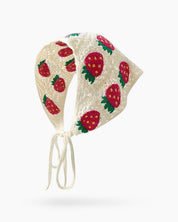 A hand-crocheted headscarf in white with adorable strawberry motifs for a sweet, whimsical look