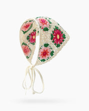 A hand-crocheted granny square headscarf in white with vibrant floral motifs for a joyful, retro charm
