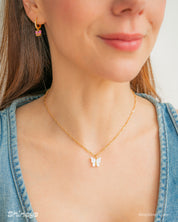 A fine gold-toned chain necklace with a modern butterfly pendant carved from glossy white resin
