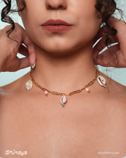 A necklace with cowrie shells, freshwater pearls, and beads on a bold gold link chain for a seaside flair